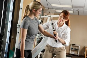 Occupational Therapy Assistant helps patient use machine to improve muscle strength