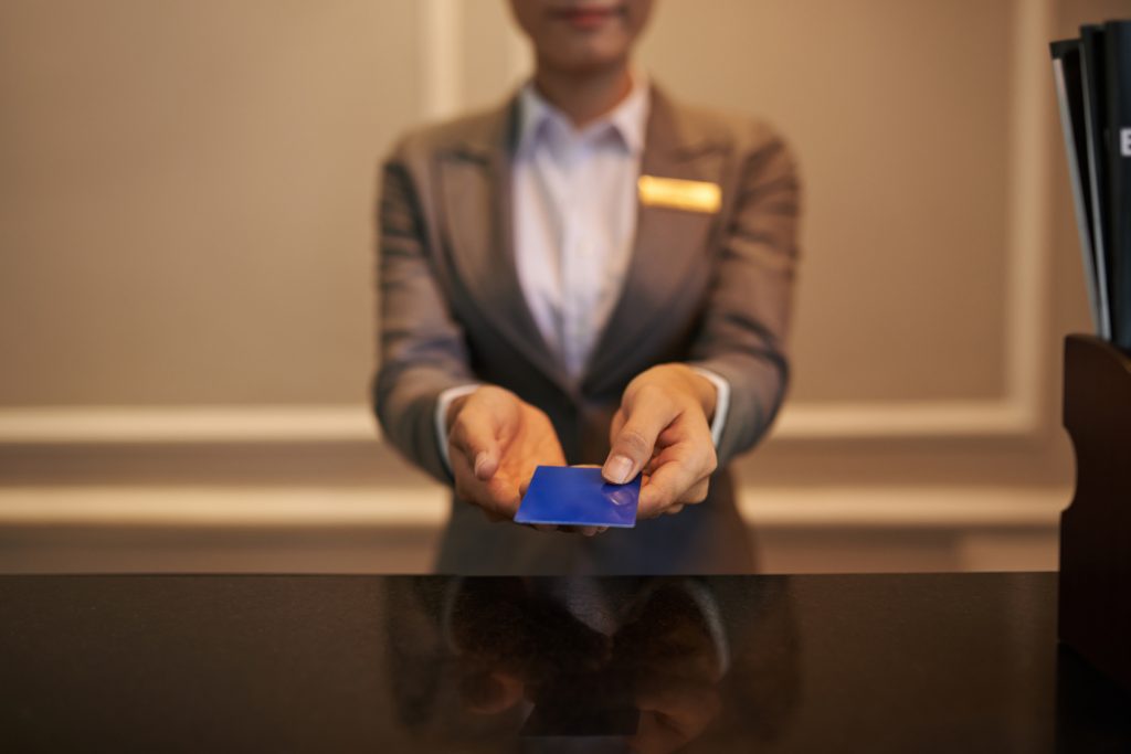 Hotel staff member handing key card to camera