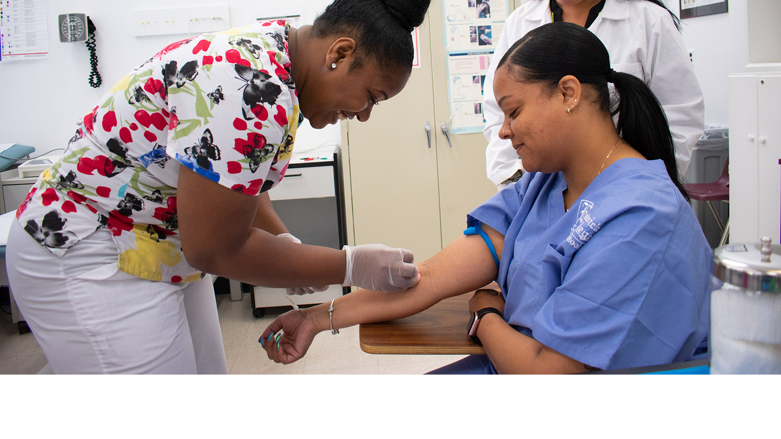 medical assisting student practices drawing blood on fellow student