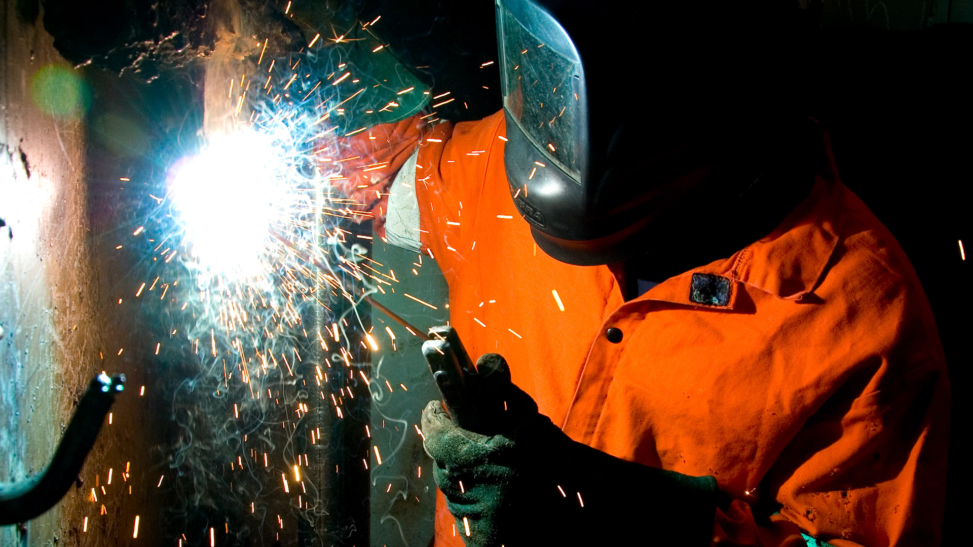 Welding student welds metal causing sparks to flow out