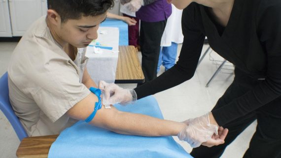 medical student practices taking blood from fellow student