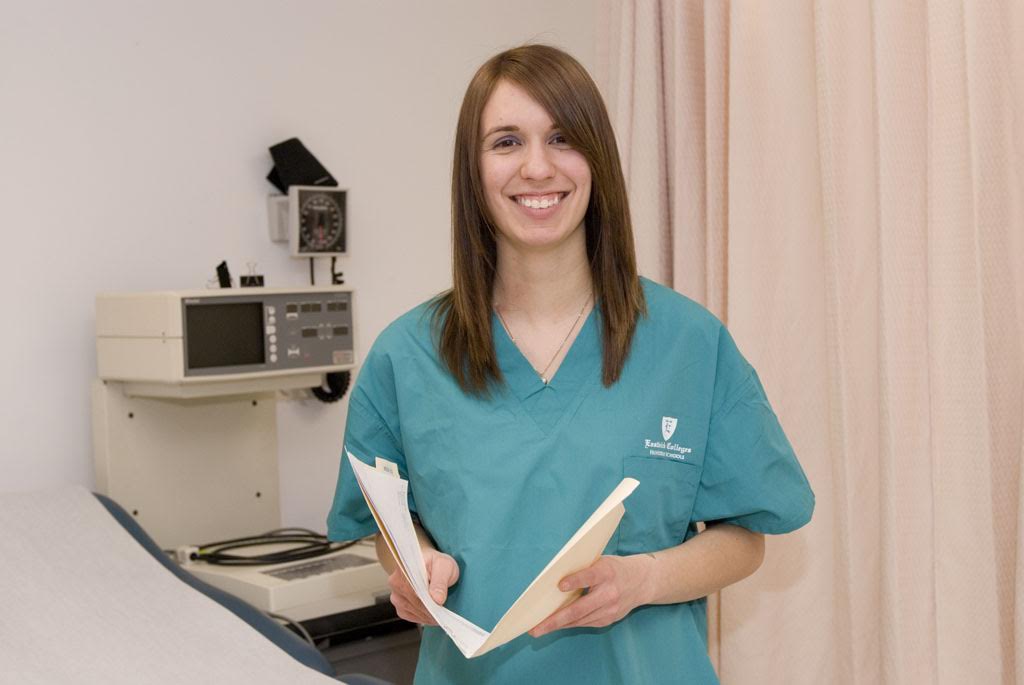 medical billing student stands beside an exam table holding a file